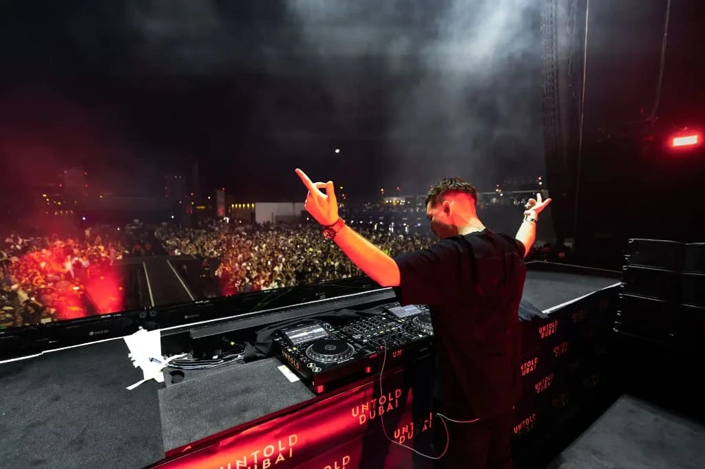 Scott Forshaw performing from behind the decks at Untold Dubai with arm raised to a massive crowd